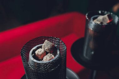 Kırmızı kömürlü Shisha nargile. Nefes alışından kıvılcımlar. Hindistan cevizi kömürü ve shisha dumanı ile modern nargile. Nargile ve kömürden kıvılcımlar, doğal ışık için geleneksel nargile kömürleri..