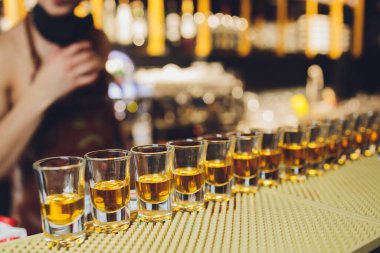 Bar tezgahında servis edilen sert alkollü içkilerin çeşitleri. Arka planda bulanık şişeler.