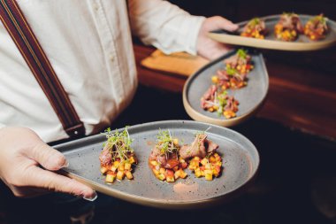 Atıştırmalık ve aperatifler. Yaban turplu ahşap bir tabakta et kesikleri ve siyah bir masada kızarmış ekmek. Taze marul, roka ve domates. Restoran menüsü. Arkaplan resmi, kopyalama alanı. Flatlay, üst görünüm