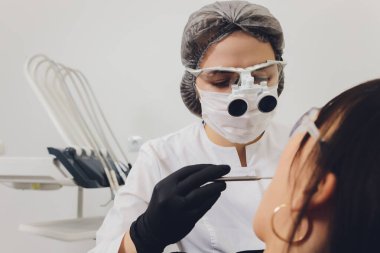 Diş hekimi ve hasta, arka planda tıbbi ekipmanlarla yapılan bir muayenede tedaviyi seçiyor.