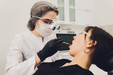 Diş hekimi ve hasta, arka planda tıbbi ekipmanlarla yapılan bir muayenede tedaviyi seçiyor.