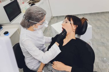 Diş hekimi ve hasta, arka planda tıbbi ekipmanlarla yapılan bir muayenede tedaviyi seçiyor.