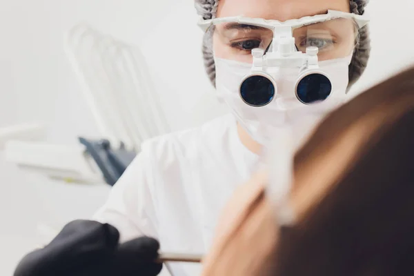 Dentista e paziente che sceglie il trattamento in una consultazione con attrezzature mediche sullo sfondo. — Foto Stock