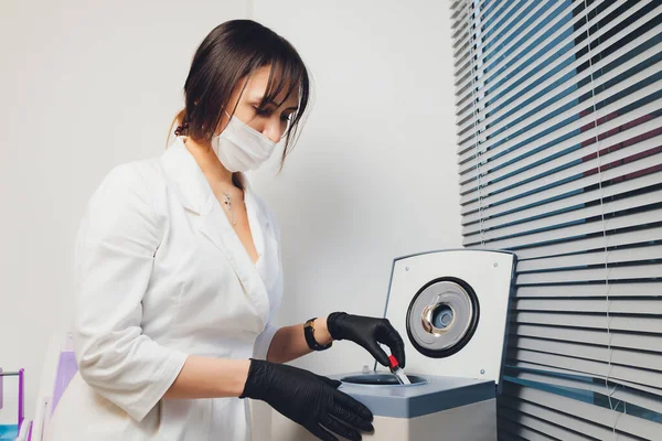 아름다운 여성 화학자가 실험실의 원심분리기에서 일부 혈액 샘플을 보고 있는 모습. — 스톡 사진