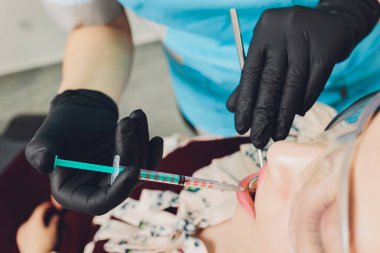 Dişçi, hastasına anestezi yapmak için iğne yapıyor..