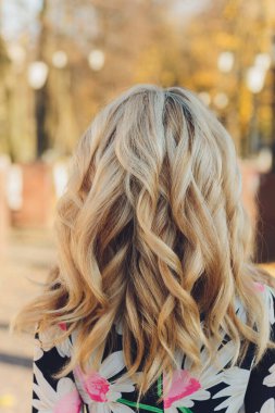 Uzun sarı saçlı, güzel bir genç kadının portresi. Sonbaharın tadını arkadan çıkarıyor. Sarı yapraklı ginkgo ağaçlarının arka planı. Sonbahar sezonu.