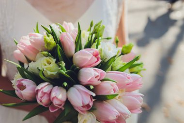 Gelinin ellerinde pembe lalelerle gelin buketi.