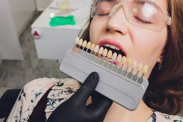 치과 의자에 앉아 있는 젊은 여성의 초상화를 닫고 치아의 색깔을 확인 해 보 세요. 치과 의사는 치과 병원에서 치료를 받는다 . Dentist. — 스톡 사진