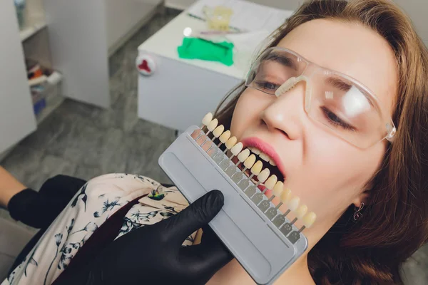 Közelkép portré fiatal nők fogorvos szék, Ellenőrizze, és válassza ki a színét a fogak. Fogorvos teszi a kezelés folyamatát a fogorvosi rendelőben.Fogorvos. — Stock Fotó