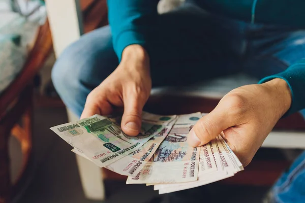 Rublos rusos en la mano de un fan.male mano sosteniendo muchos de los billetes rusos.La transferencia de dinero.El aislado cinco milésimas de rublos rusos denominaciones en una mano. — Foto de Stock