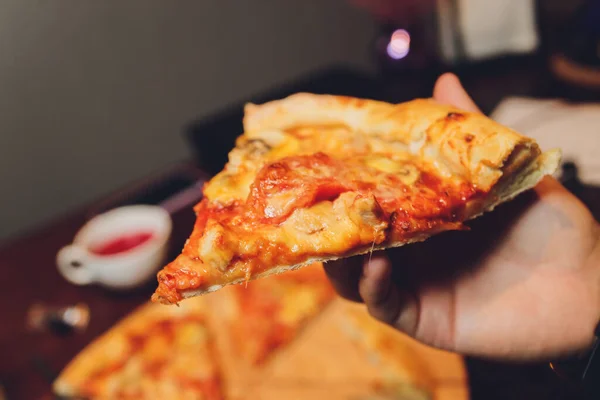 Közelkép egy női kézről, amint egy szelet pizzát tart.. — Stock Fotó