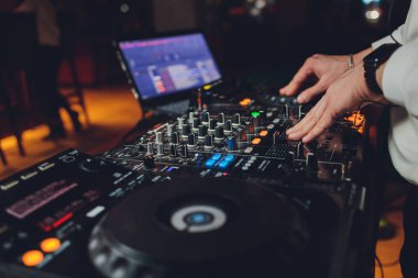 DJ 'ler ses ayarlarını kontrol eden dizüstü bilgisayarı ve konsolu karıştırıyor.
