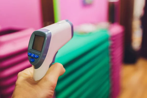 Temperature measurement by electronic infrared thermometer of a womans hand at the entrance to a supermarket. Coronavirus pandemic. Lifestyle. — Stock Photo, Image