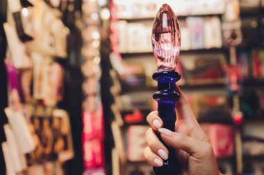 Anal glass butt plug with a fluffy tail with female hands. Toy for adult games.