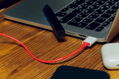 POD e-sigara veya nikotin buhar makinesi modern dizüstü bilgisayarda Podlarla şarj ediliyor.