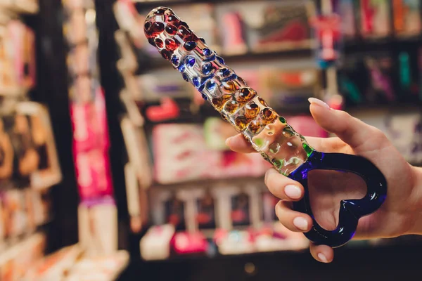 Anal glass butt plug with a fluffy tail with female hands. Toy for adult games.