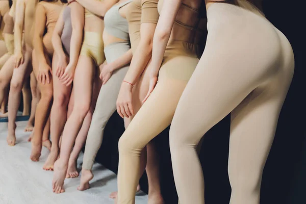 Many girls training in studio ballet, long woman legs ass bracing, wearing sexual flesh color bodysuit. — Zdjęcie stockowe