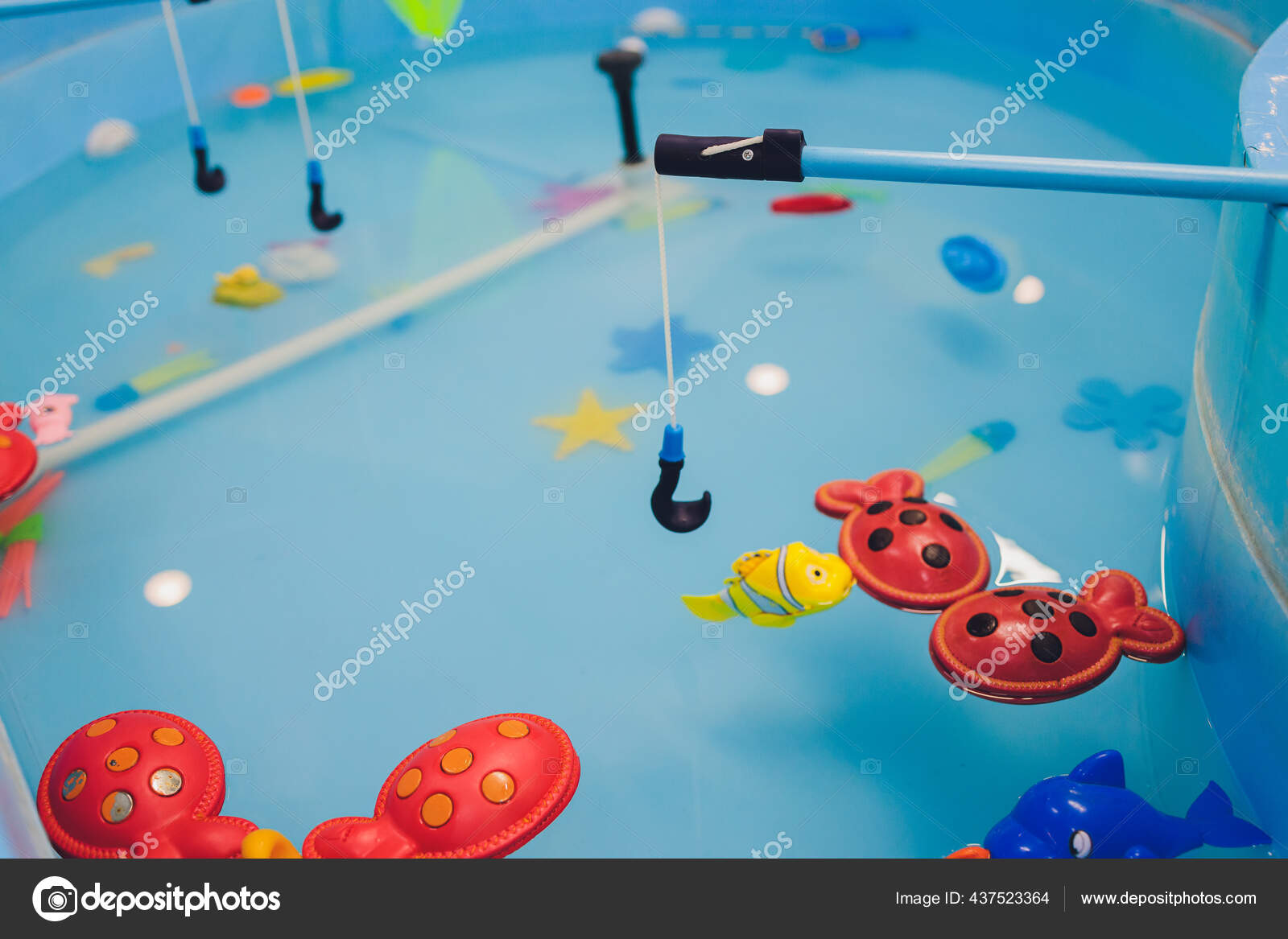 Fishing in the paddling pool. Childrens toys in the pool. Toy fish fishing  rod. Cheerful children fishing, fishing in the paddling pool. — Stock Photo  © vershinin.photo #437523364