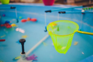 Kürek havuzunda balık tutmak. Havuzda çocuk oyuncakları var. Oyuncak balık oltası. Neşeli çocuklar balık tutuyor, havuzda balık tutuyor..