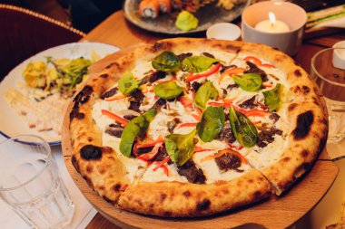 Üstünde taze fesleğen yaprakları olan ince hamurlu pizza. Bir dilim pizza. Ev yapımı yemek. İtalyan vejetaryen pizzası. Lezzetli ve sağlıklı bir yemek için konsept. Kırsal ahşap arkaplan.