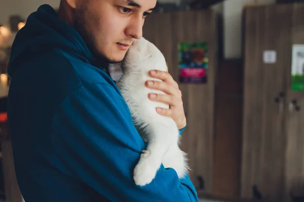 Genç adam beyaz bir kediyi yakından tutuyor.. — Stok fotoğraf