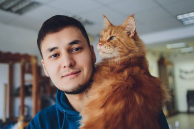 Maine Zencefilli Kedi 'yi tutan genç adam.