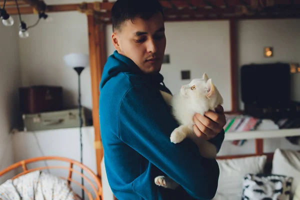 Молодой человек держит белую кошку крупным планом. — стоковое фото