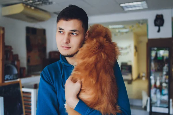 Молодой человек держит в руках имбирную кошку мейн кун. — стоковое фото
