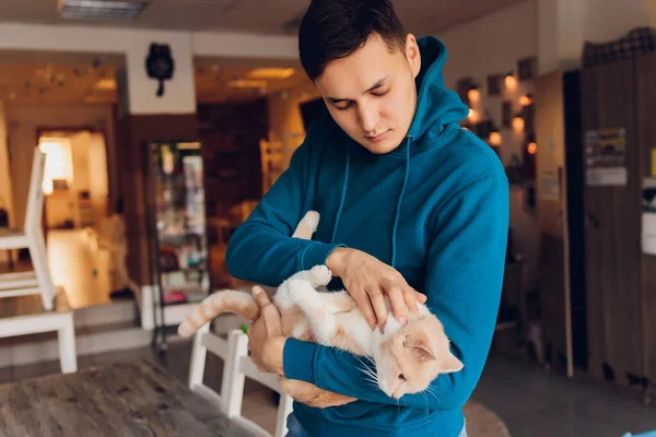 Молодой человек держит белую кошку крупным планом. — стоковое фото