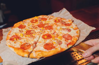 Domatesli taze fırınlanmış Pepperoni Pizza, Pepperoni ve Peynir kesim tahtasında Grunge arka planında yakın plan..