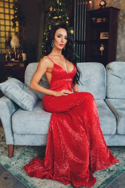 Yeni yıl stüdyosunda poz veren güzel bir kadın, yeni yıl fotoğraf çekimi. İnce bacaklı, lüks elbiseli güzel bir kız. Noel, kış, mutluluk konsepti.