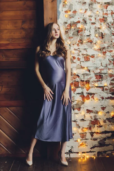 Молода красива вагітна жінка з світлим волоссям і ніжним макіяжем в модному платті позує біля студії . — стокове фото