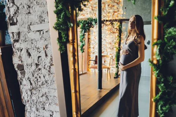 Una donna incinta felice guarda amorevolmente un riflesso di se stessa e del suo nascituro in uno specchio. — Foto Stock