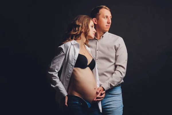 妊娠中の女性彼女の夫保持彼女のおなか.黒の背景に若い魅力的な妊娠中の女性の美しい腹. — ストック写真