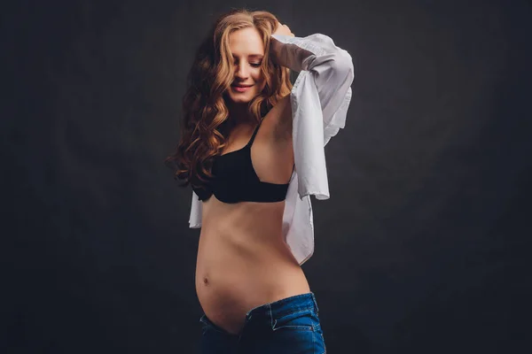 Fiatal gyönyörű elegáns terhes nő pózol fekete fehérnemű. — Stock Fotó