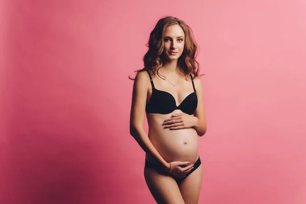 Retrato de bandagem de gravidez vestida em mulher grávida em roupa interior para reduzir a dor nas costas em fundo rosa com espaço de cópia. Conceito de cinto de suporte abdominal ortopédico. — Fotografia de Stock