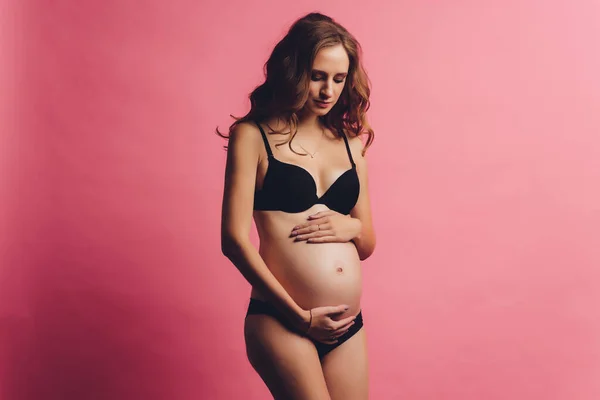 Retrato de vendaje de embarazo vestido en mujer embarazada en ropa interior para reducir el dolor de espalda en el fondo rosa con espacio para copiar. Concepto de cinturón de soporte abdominal ortopédico. —  Fotos de Stock