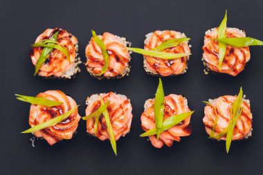 Siyah arka planda somon balıklı Maki Suşi Rolls. Zencefil ve wasabi ile. Suşi menüsü. Japon yemeği. Sushi dürümlü lezzetli Japon yemeklerini yakından çek. Yatay fotoğraf.