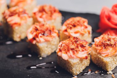 Siyah arka planda somon balıklı Maki Suşi Rolls. Zencefil ve wasabi ile. Suşi menüsü. Japon yemeği. Sushi dürümlü lezzetli Japon yemeklerini yakından çek. Yatay fotoğraf.