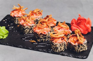Siyah arka planda somon balıklı Maki Suşi Rolls. Zencefil ve wasabi ile. Suşi menüsü. Japon yemeği. Sushi dürümlü lezzetli Japon yemeklerini yakından çek. Yatay fotoğraf.