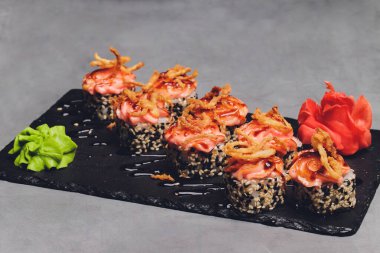 Siyah arka planda somon balıklı Maki Suşi Rolls. Zencefil ve wasabi ile. Suşi menüsü. Japon yemeği. Sushi dürümlü lezzetli Japon yemeklerini yakından çek. Yatay fotoğraf.