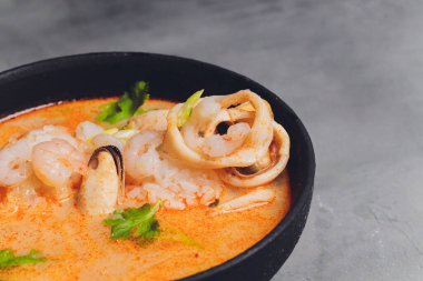 Baharatlı Tayland çorbası Tom Yam, hindistan cevizi sütü, acı biber ve deniz mahsulü karides ve somon ile siyah arka planda. Asya mutfağı, restoran menüsü.