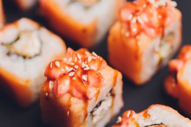 Siyah arka planda somon balıklı Maki Suşi Rolls. Zencefil ve wasabi ile. Suşi menüsü. Japon yemeği. Sushi dürümlü lezzetli Japon yemeklerini yakından çek. Yatay fotoğraf.