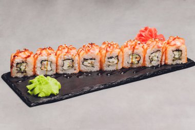 Siyah arka planda somon balıklı Maki Suşi Rolls. Zencefil ve wasabi ile. Suşi menüsü. Japon yemeği. Sushi dürümlü lezzetli Japon yemeklerini yakından çek. Yatay fotoğraf.