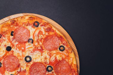 Pizza pepperonisi, mozzarella, siyah arka planda kekik otu..