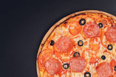 Pizza pepperonisi, mozzarella, siyah arka planda kekik otu..