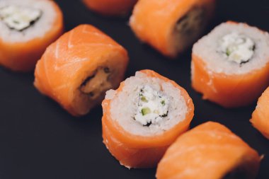 Geleneksel taze Japon suşisi siyah arka planda yuvarlanıyor..