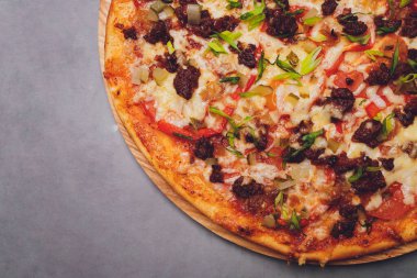 Tahtada kağıt üzerinde pizza. Siyah bir masada pizza, yakın plan. Sağlıklı sıcak yemek..