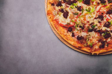 Tahtada kağıt üzerinde pizza. Siyah bir masada pizza, yakın plan. Sağlıklı sıcak yemek..