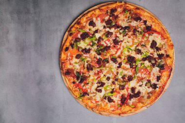 Tahtada kağıt üzerinde pizza. Siyah bir masada pizza, yakın plan. Sağlıklı sıcak yemek..